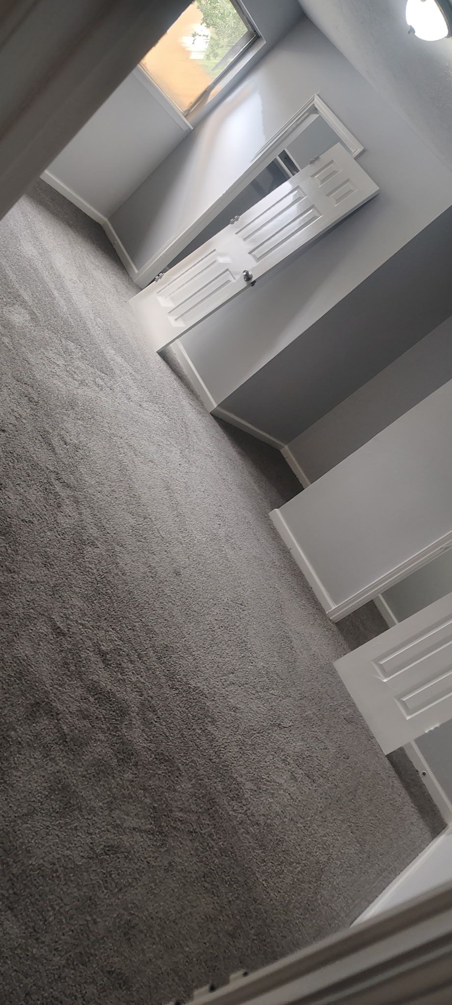 Looking down a stairwell with gray carpet and white walls.