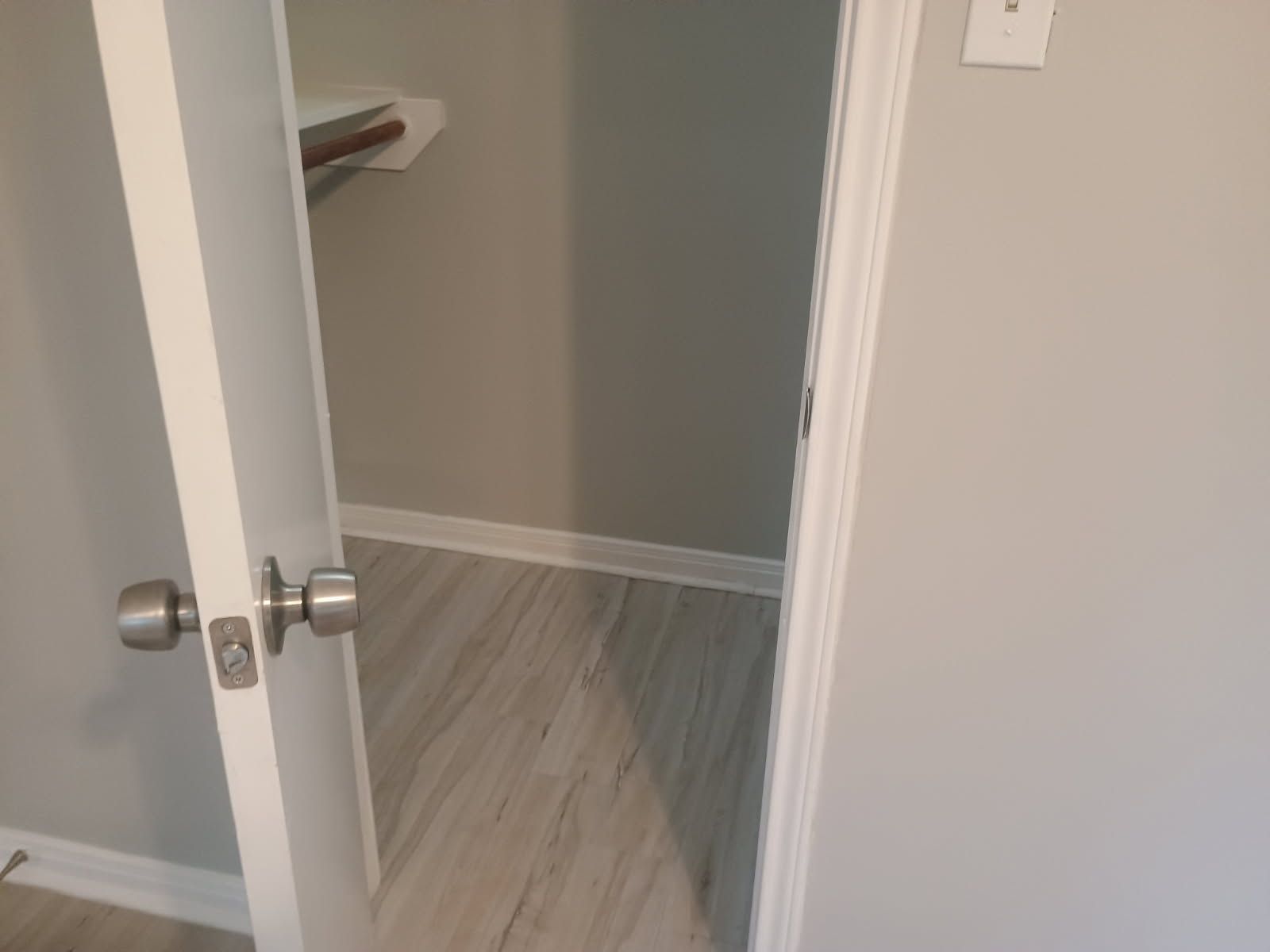 Open doorway into a small closet with a shelf and gray walls.