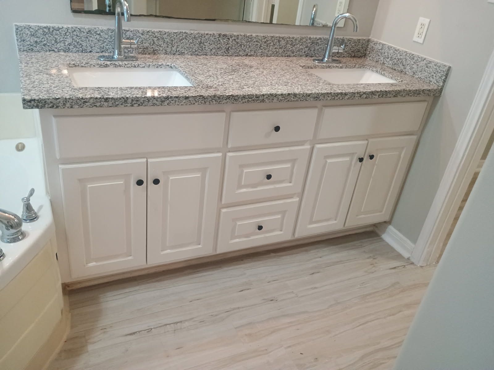 White double-sink vanity with granite countertop in a bathroom with light-colored flooring.