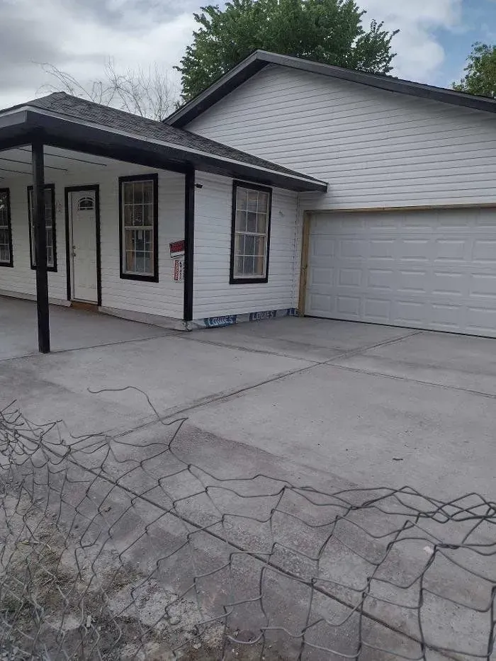 White house with black trim and a concrete driveway.