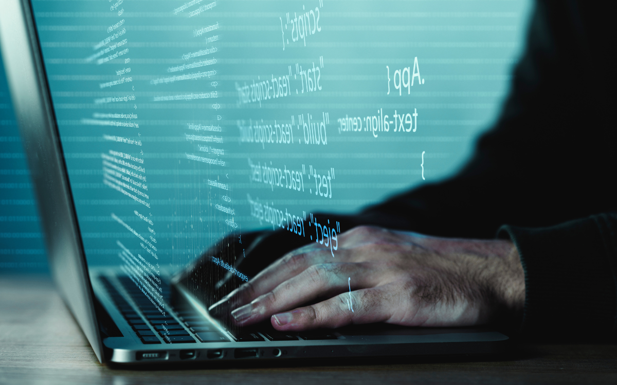 A person is typing on a laptop computer in a dark room.