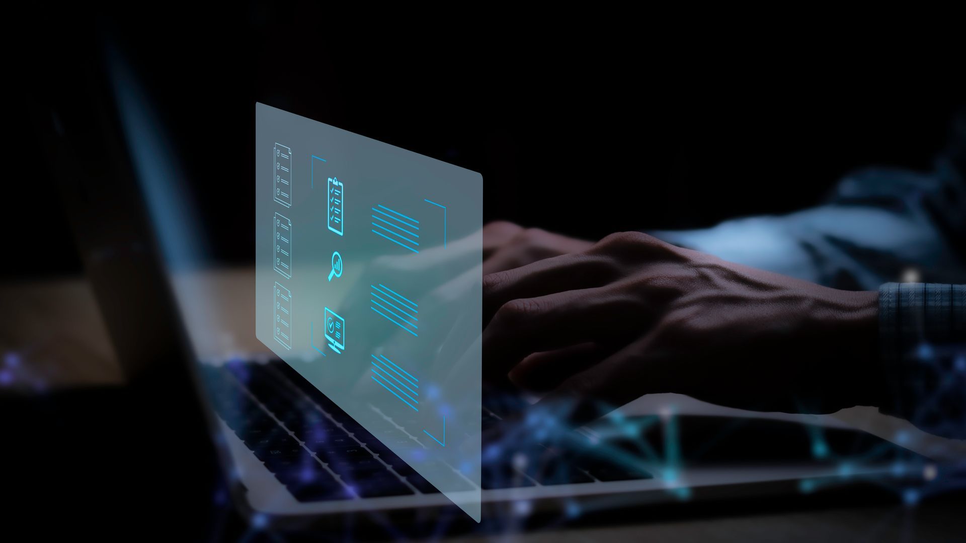 A person is typing on a laptop computer in a dark room.