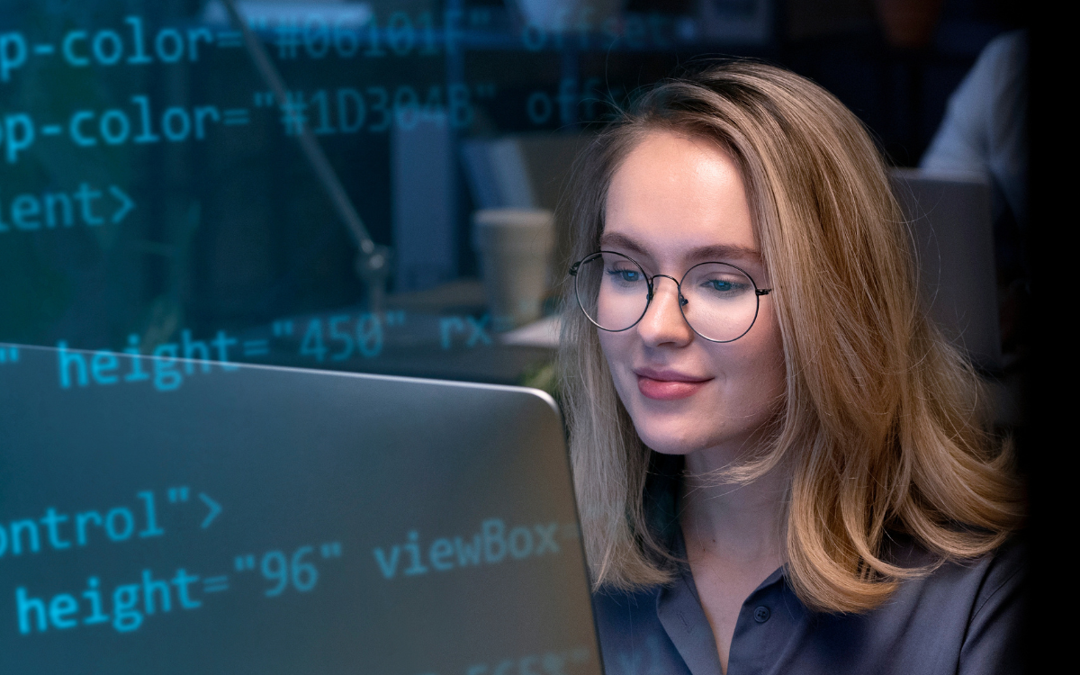 A woman wearing glasses is sitting in front of a laptop computer.