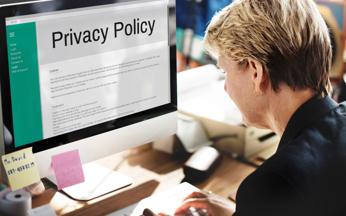 A woman is sitting in front of a computer with a privacy policy on the screen.