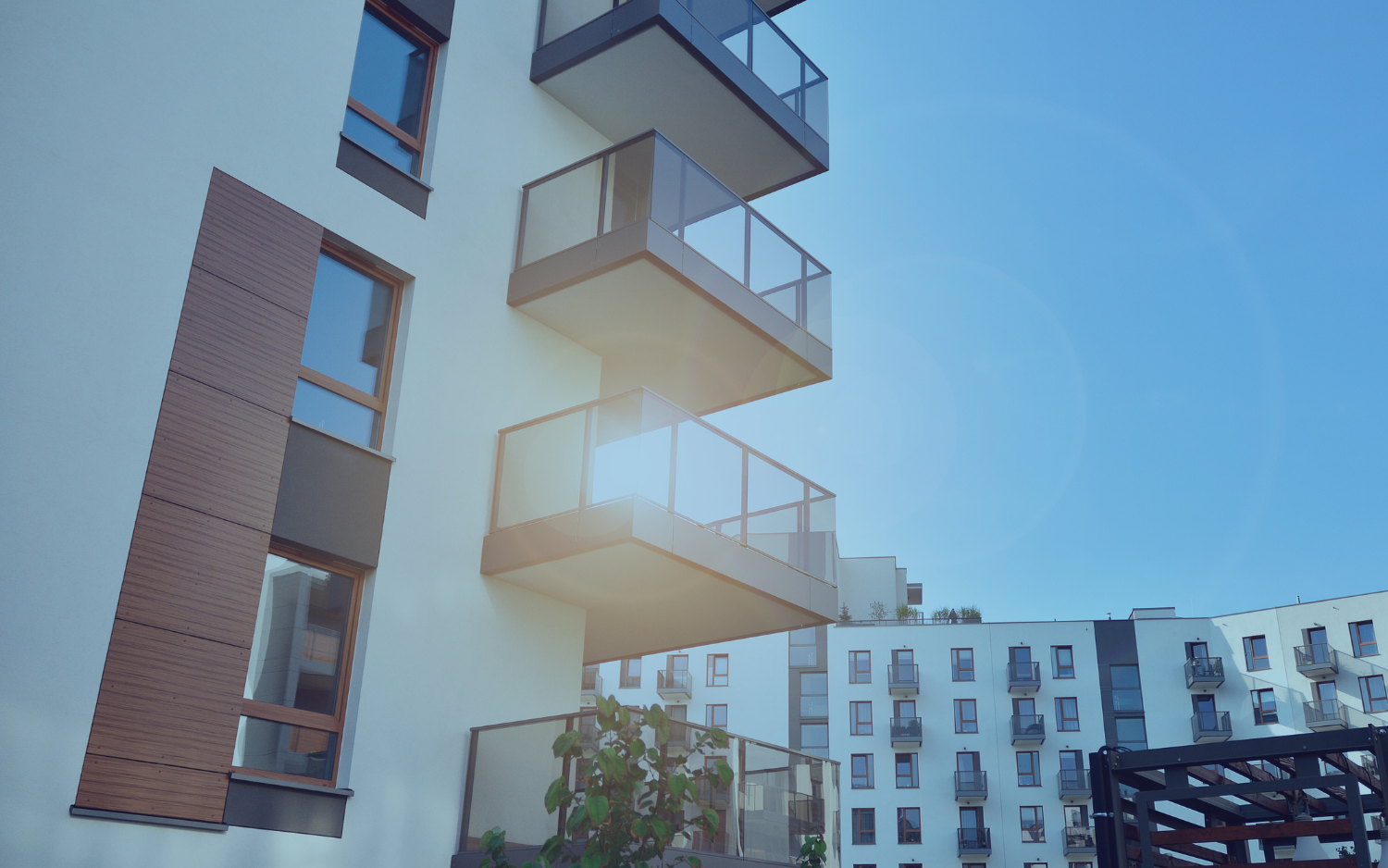 Modern apartment building with balconies under a bright blue sky.