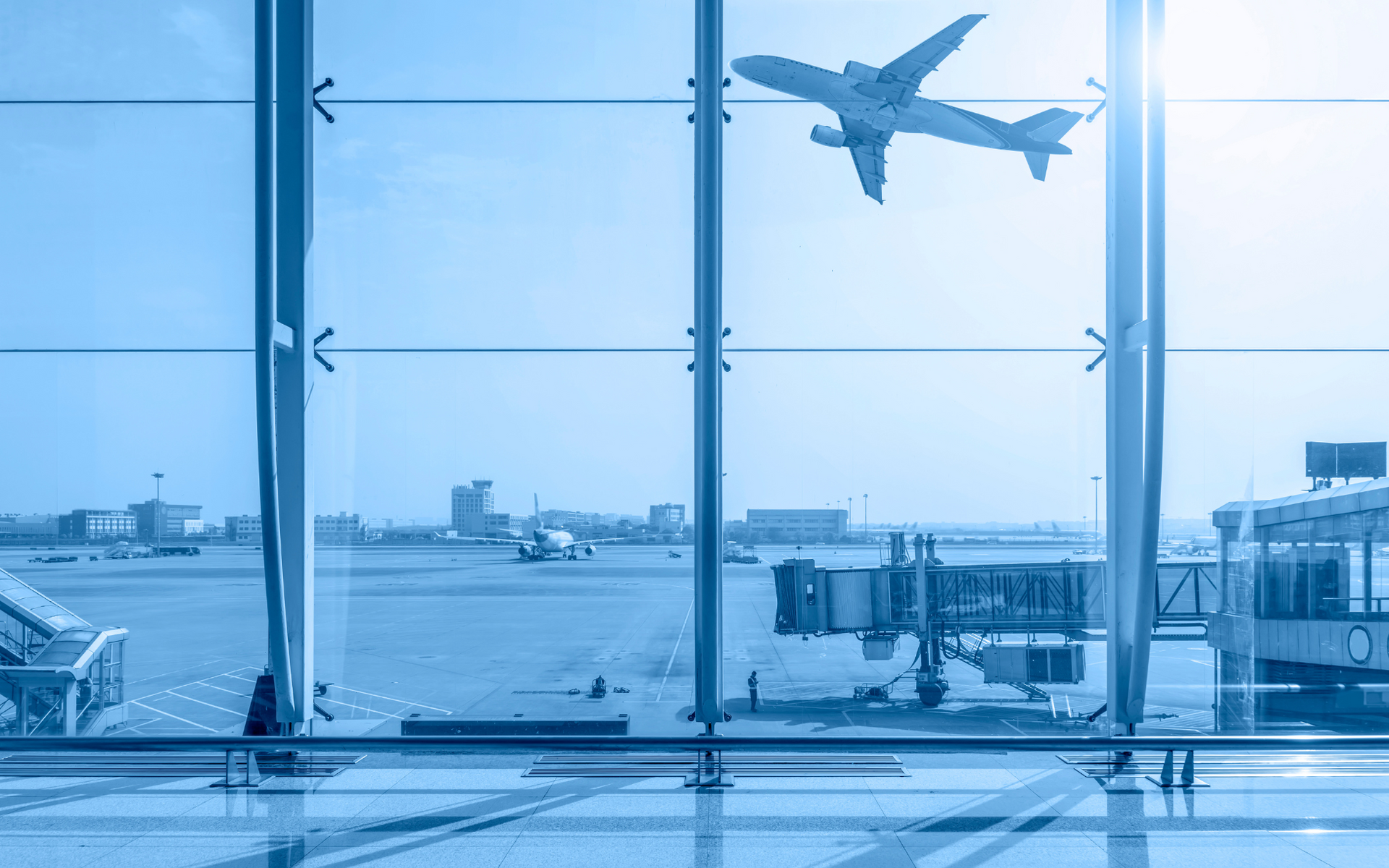 An aeroplane taking off from an airport is seen through a window, with a blue-toned colour scheme.