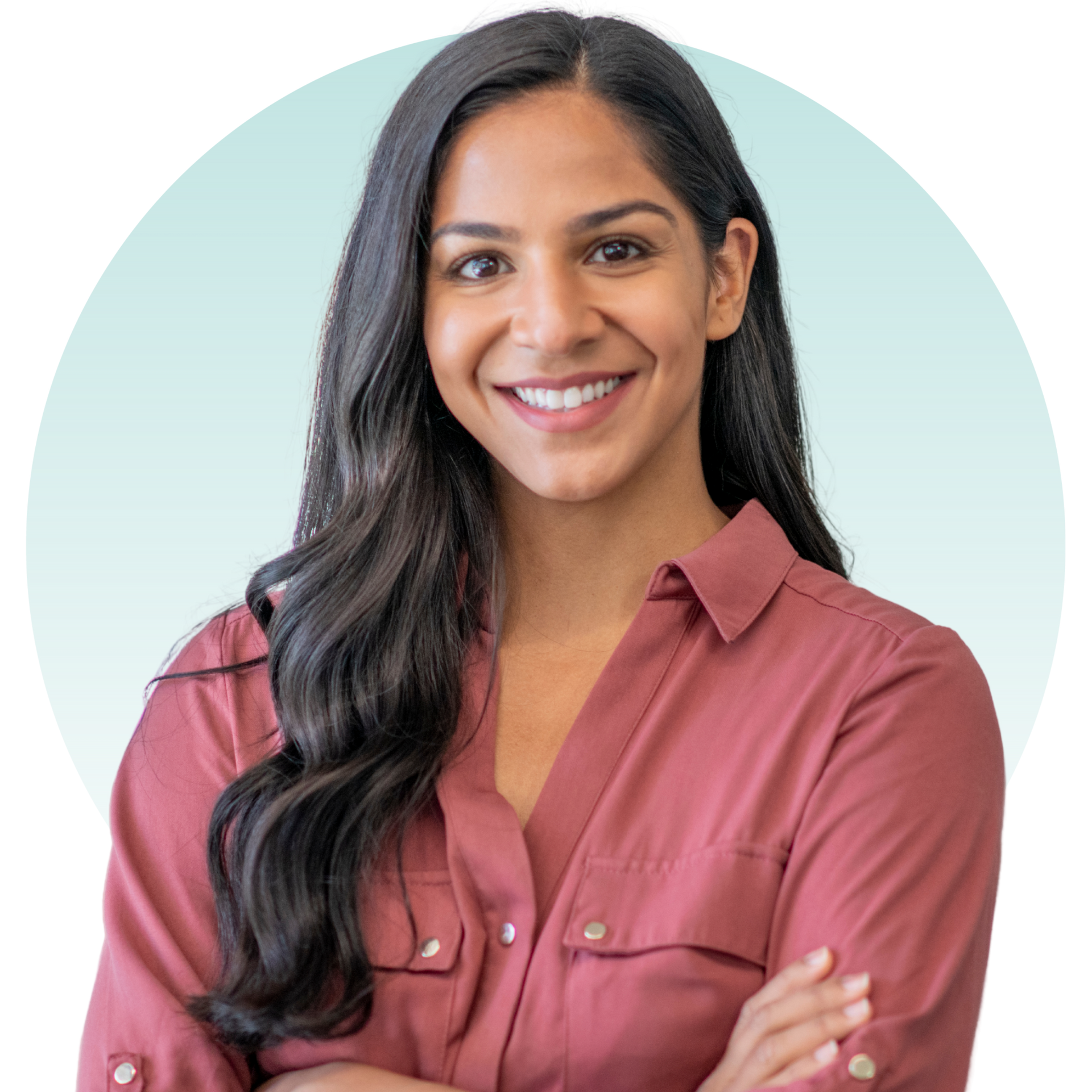 Smiling woman with dark hair and arms crossed, wearing a red shirt against a light blue backdrop.