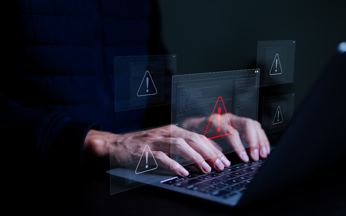 A person is typing on a laptop computer in a dark room.