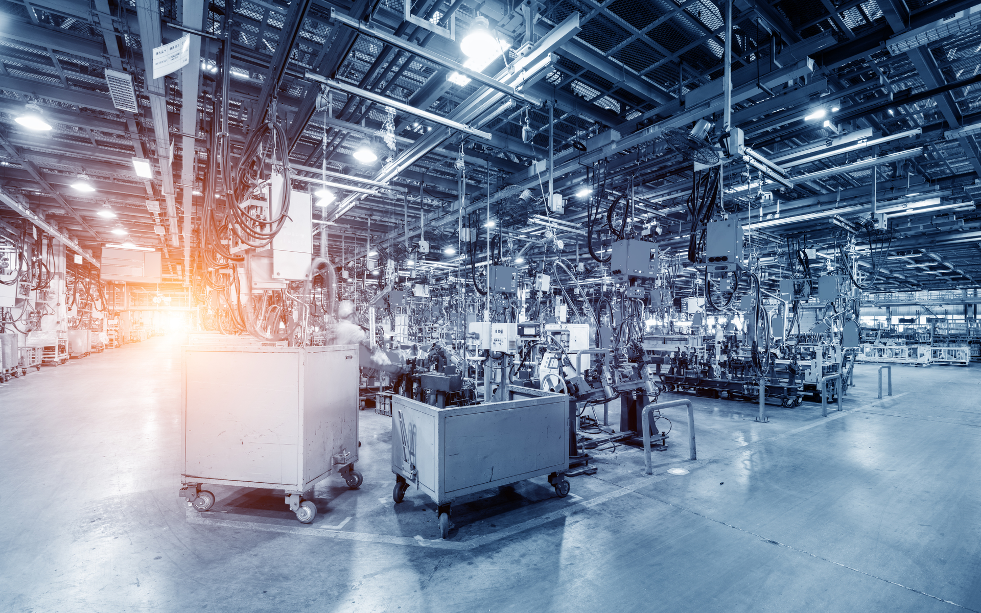 Industrial factory interior with machinery, assembly lines, and carts.