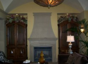 Fireplace flanked by dark wood cabinets with floral arrangements, in a room with a yellow wall and a chandelier.