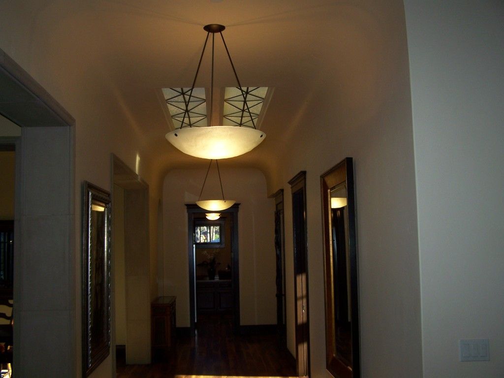 Hallway with hanging lights, mirrors, and wooden floor.