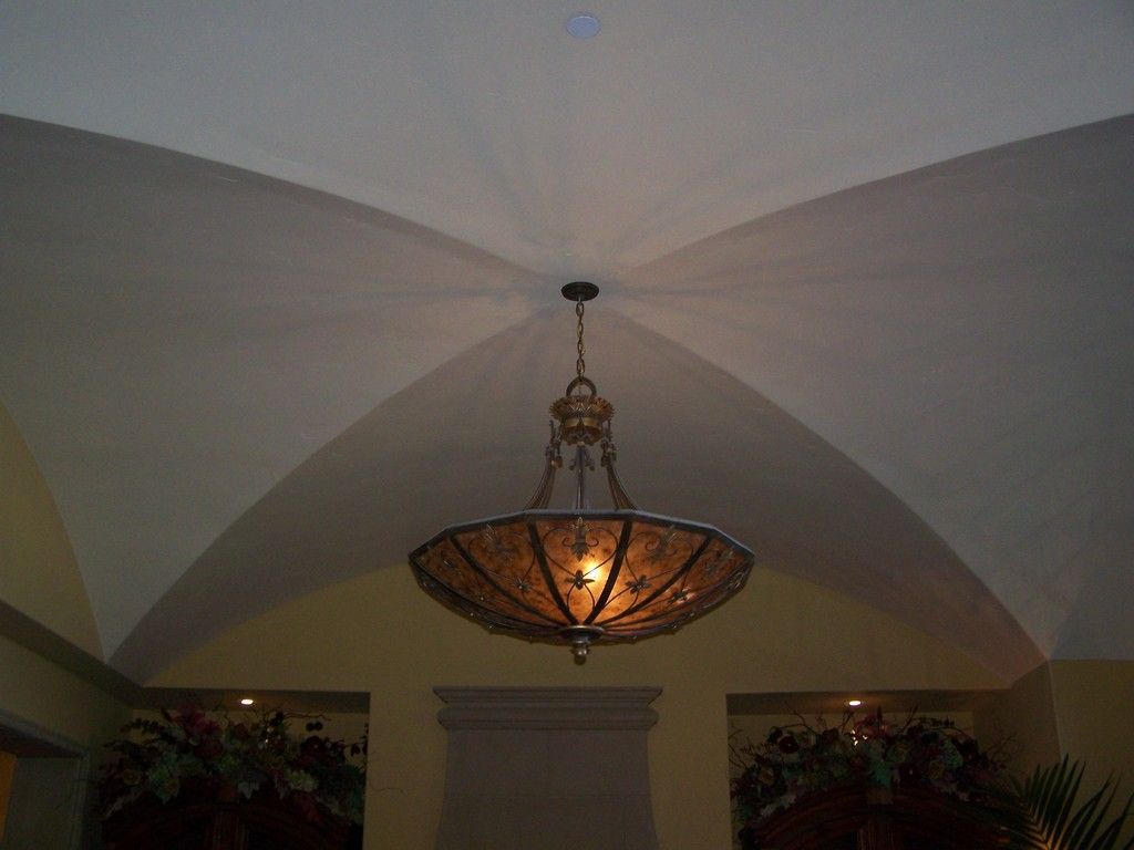 Ornate chandelier hanging from a white vaulted ceiling.