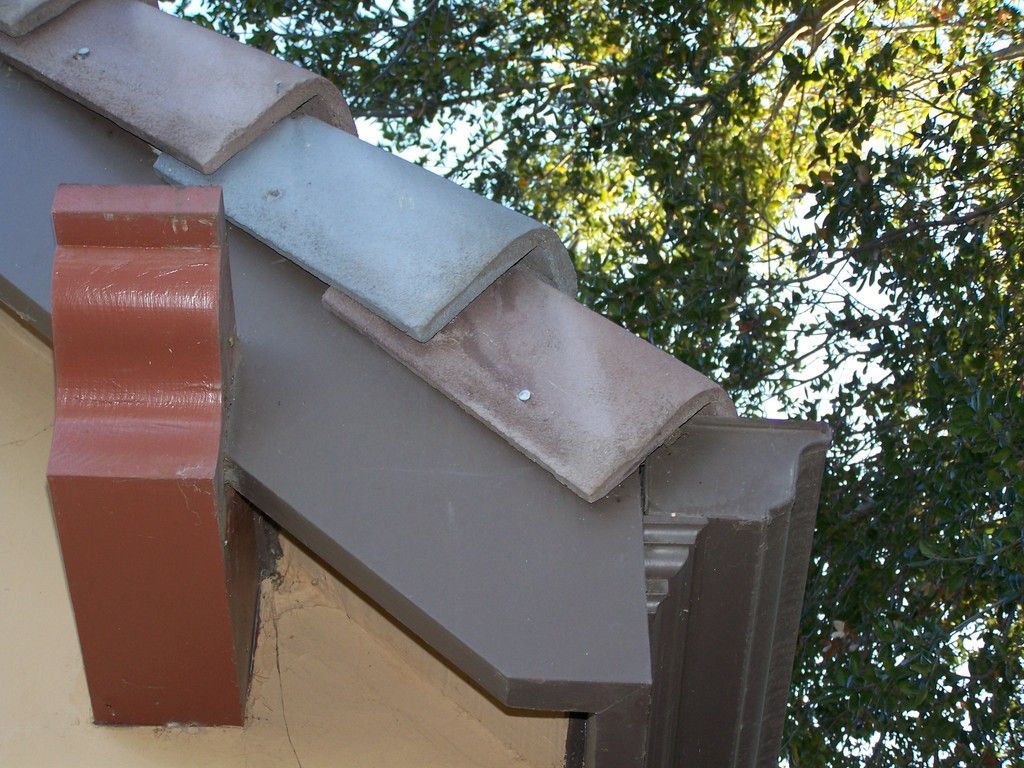 Brown building corner with decorative trim and partially visible tile roof.
