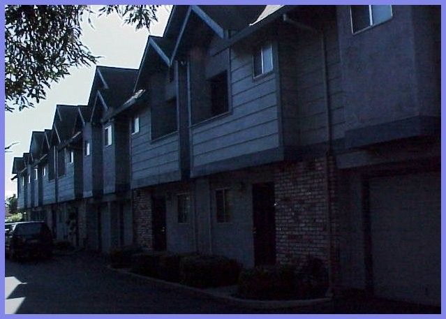 Row of multi-story townhomes with gray siding and brick accents.