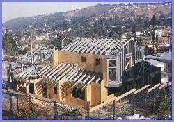 House under construction, wood frame, hillside setting, with a partially completed roof.
