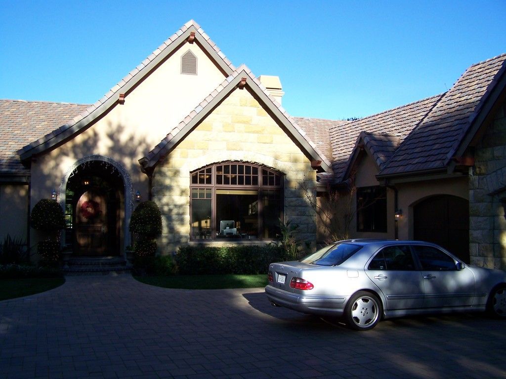 Stone house with a silver car parked in the driveway.