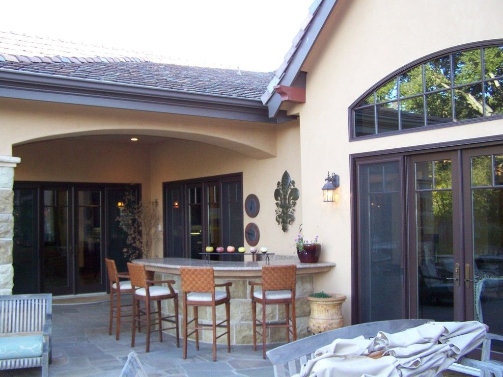Patio with a bar, seating, and arched window on a beige stucco building.