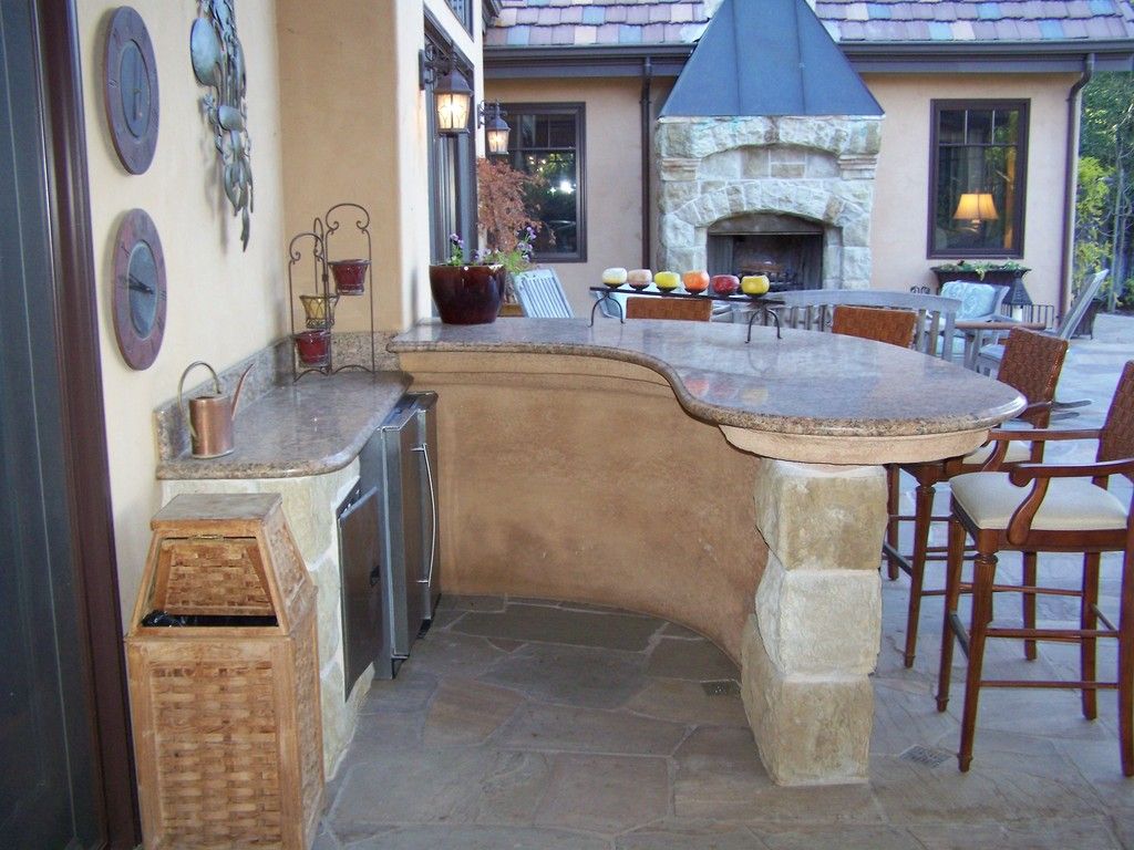 Two-story house with tan stucco, stone accents, brown shutters, and a small front yard.