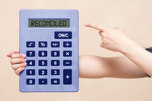 A person points at a calculator displaying 