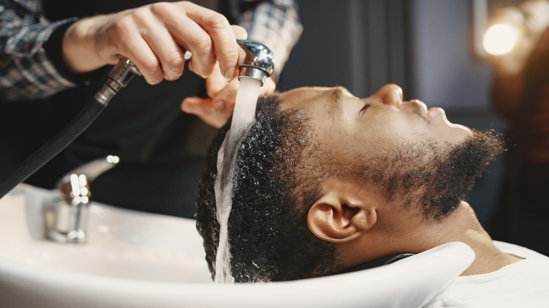Person getting hair washed at a salon; water pouring over their head.