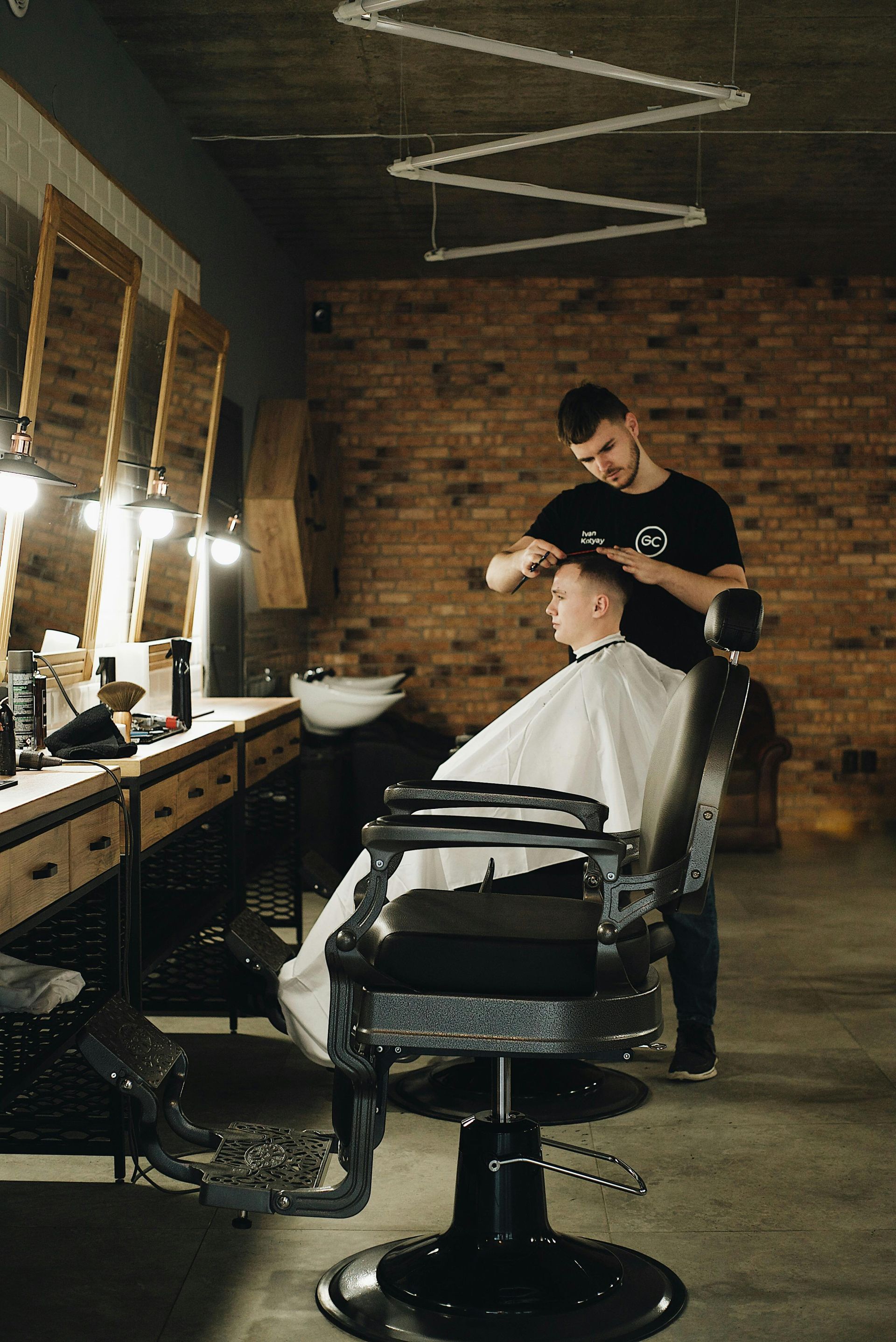 Barber giving a client a haircut in a brick-walled shop.