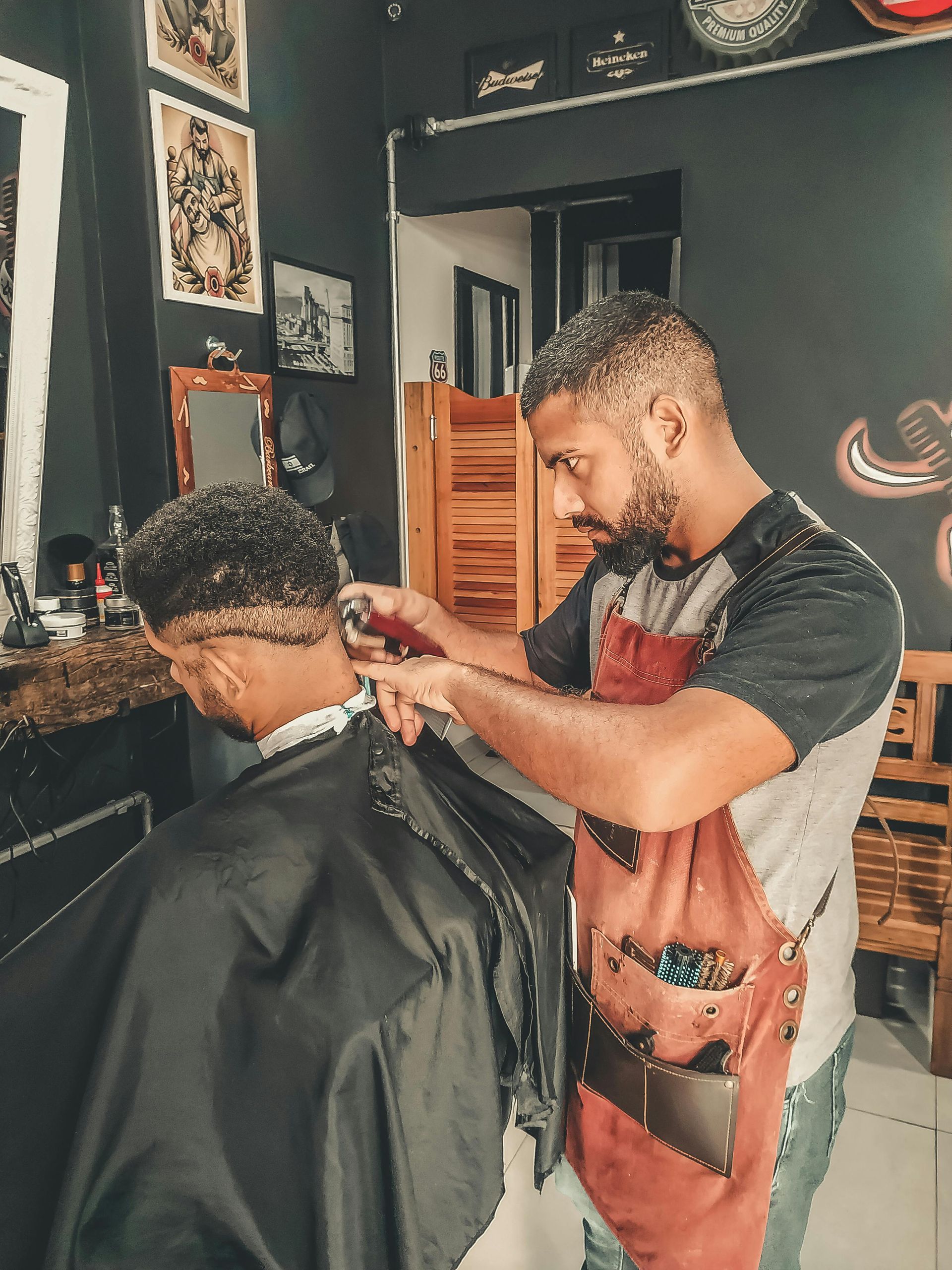 Barber cutting a client's hair with clippers in a dimly lit barbershop.