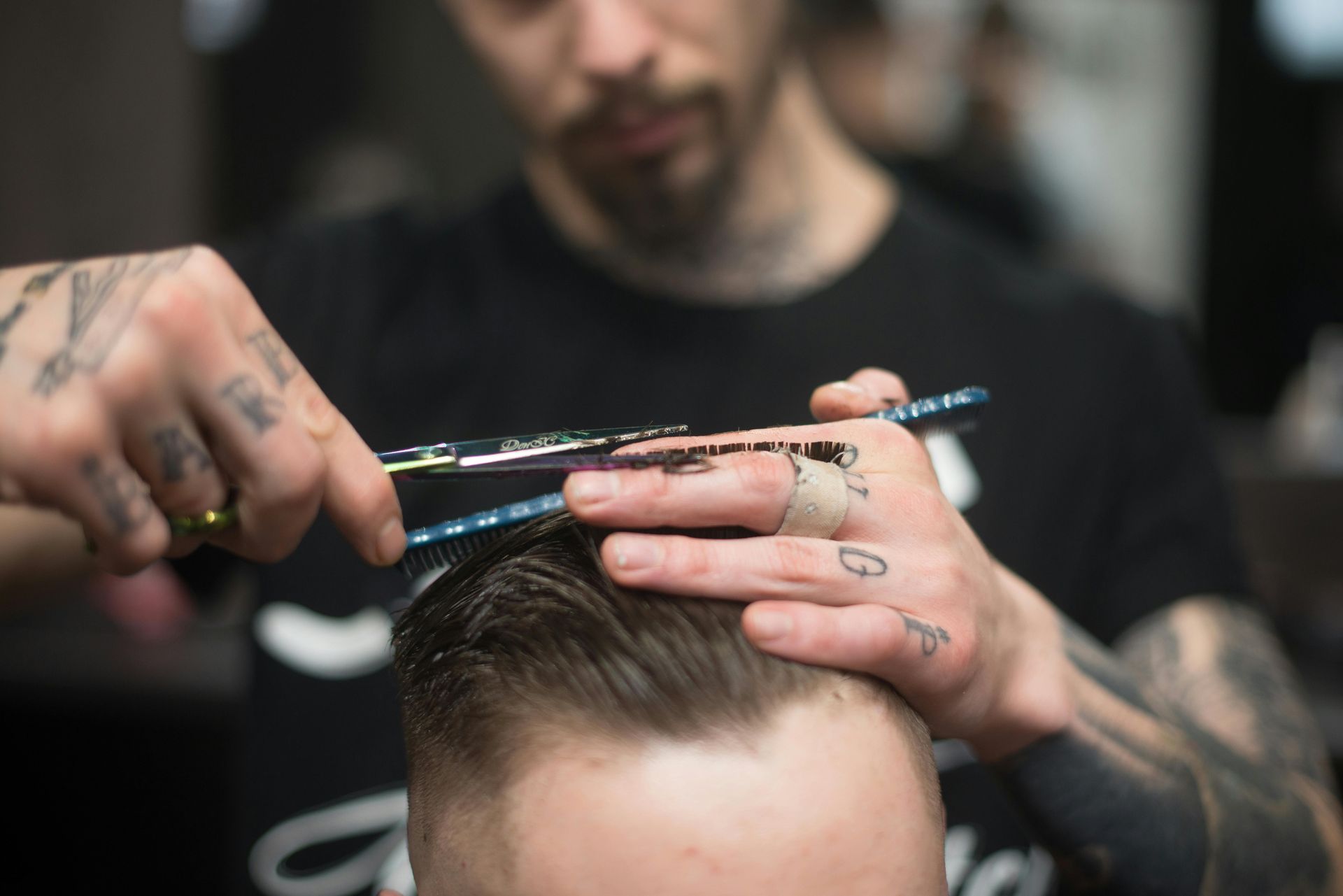Barber cutting a client's hair with scissors; close-up of hands and hair.