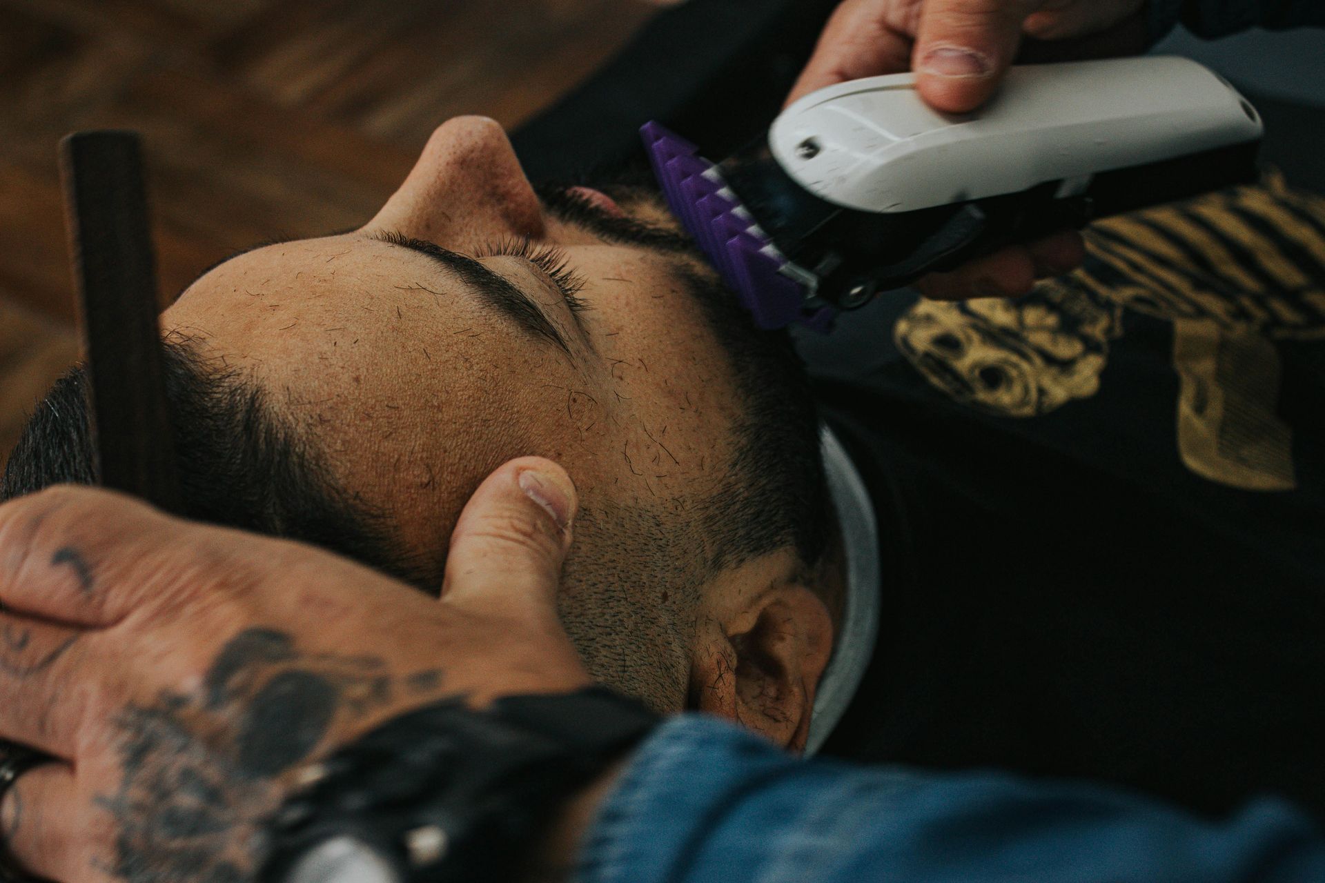 Barber using clippers and comb on a client's face.