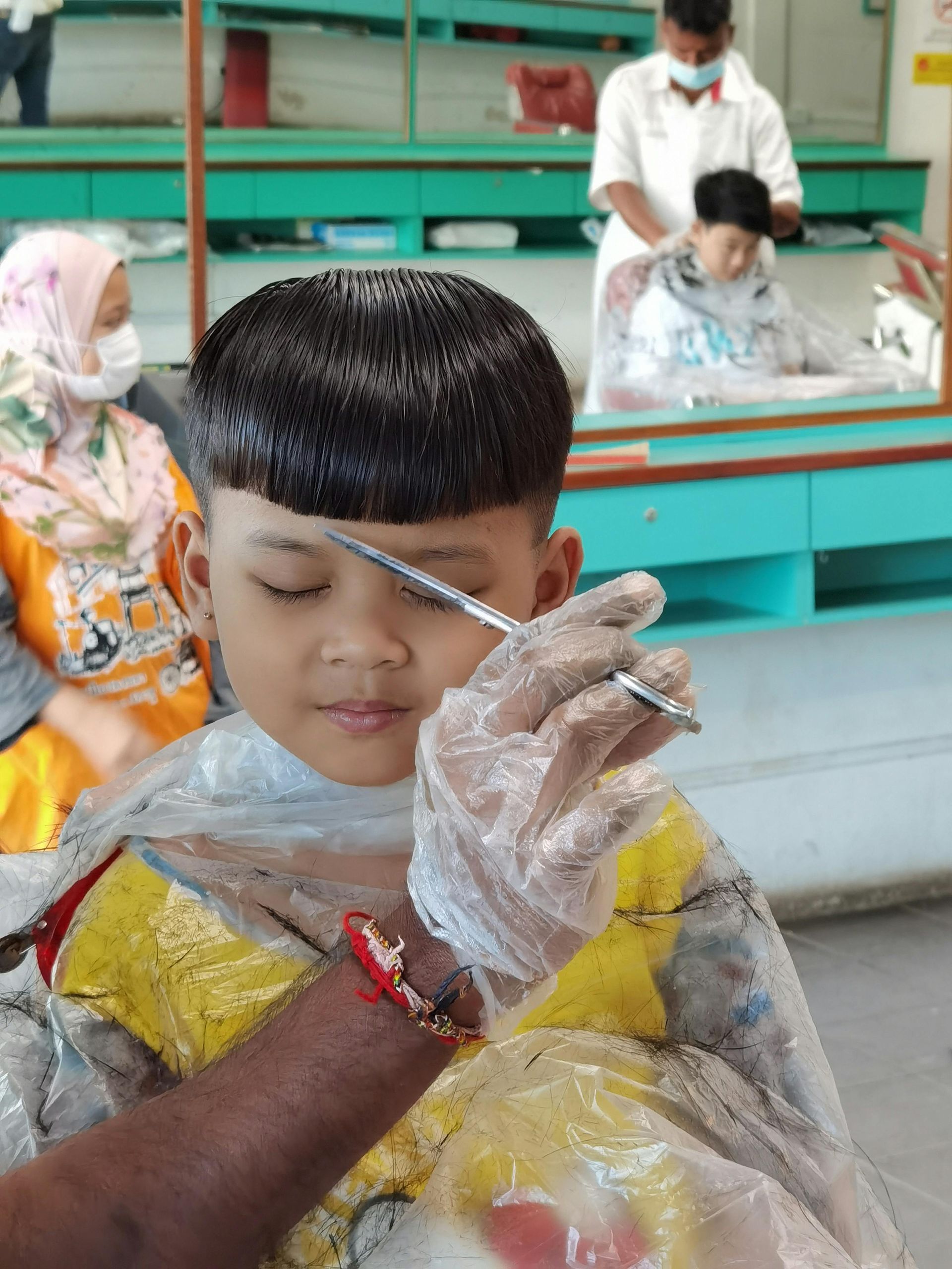 Man getting a haircut, barber spraying water on his head. Faded haircut, full beard. Outdoors, day.