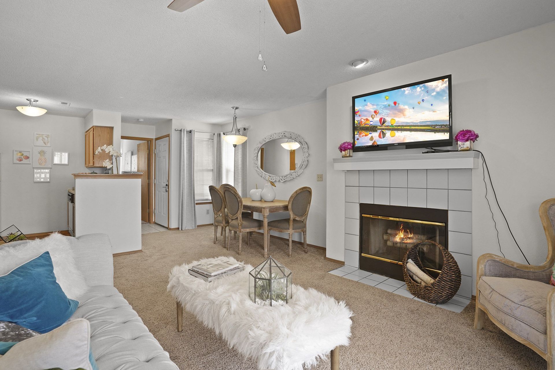 A living room with a fireplace and a television mounted above it.