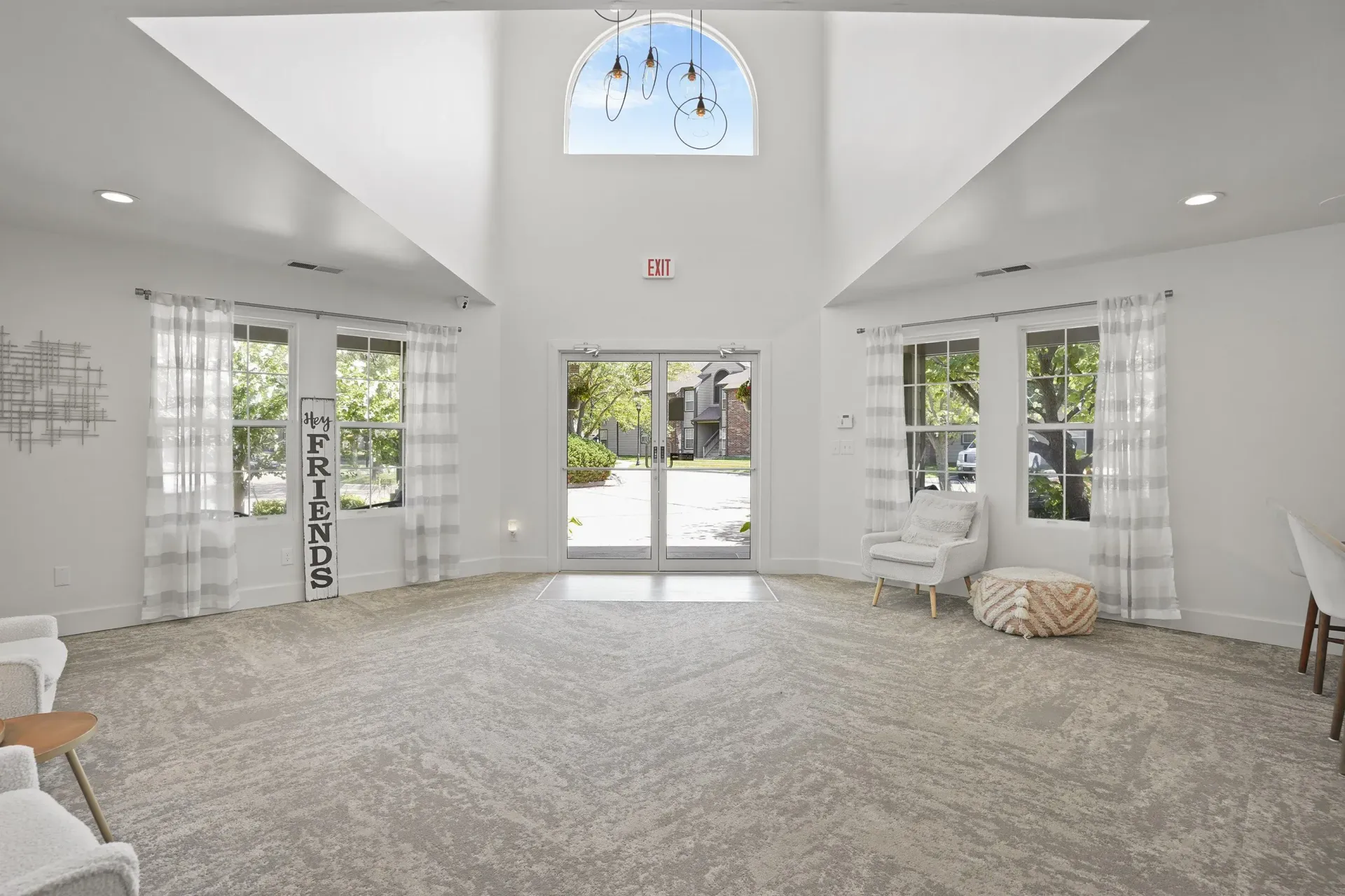 A spacious room with a carpeted floor and a large window with curtains.