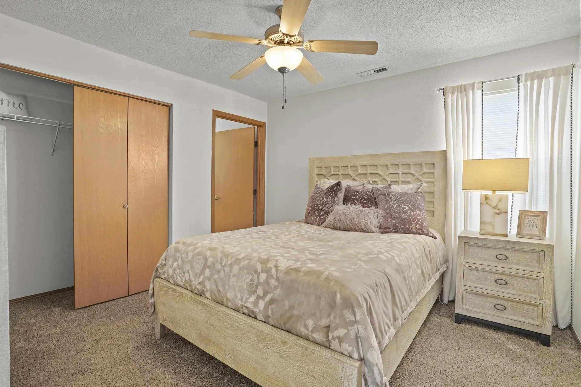 A bedroom with a bed, dresser, and closet.