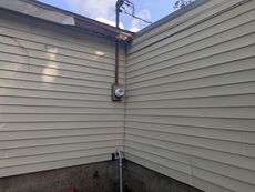 A corner of a house with a light on the side of it.