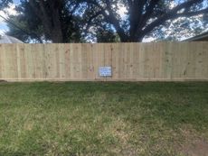 A wooden fence is sitting in the middle of a lush green yard.