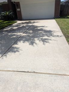 A concrete driveway leading to a garage with a tree shadow on it.