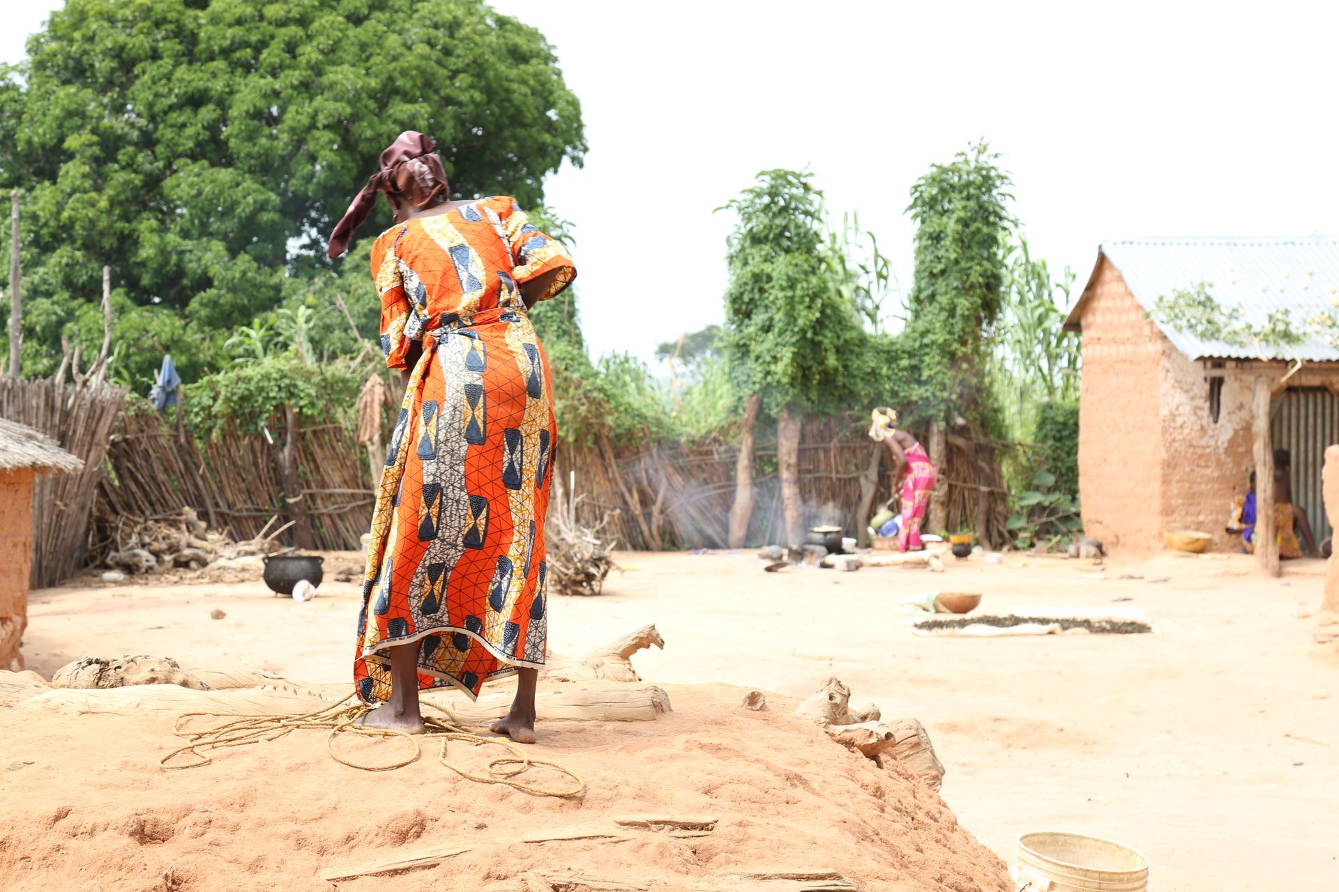 Woman in colorful dress in a village, fetching water from a well.