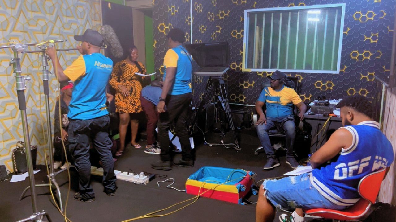 People in a recording studio setting; some are working, others are socializing near equipment.