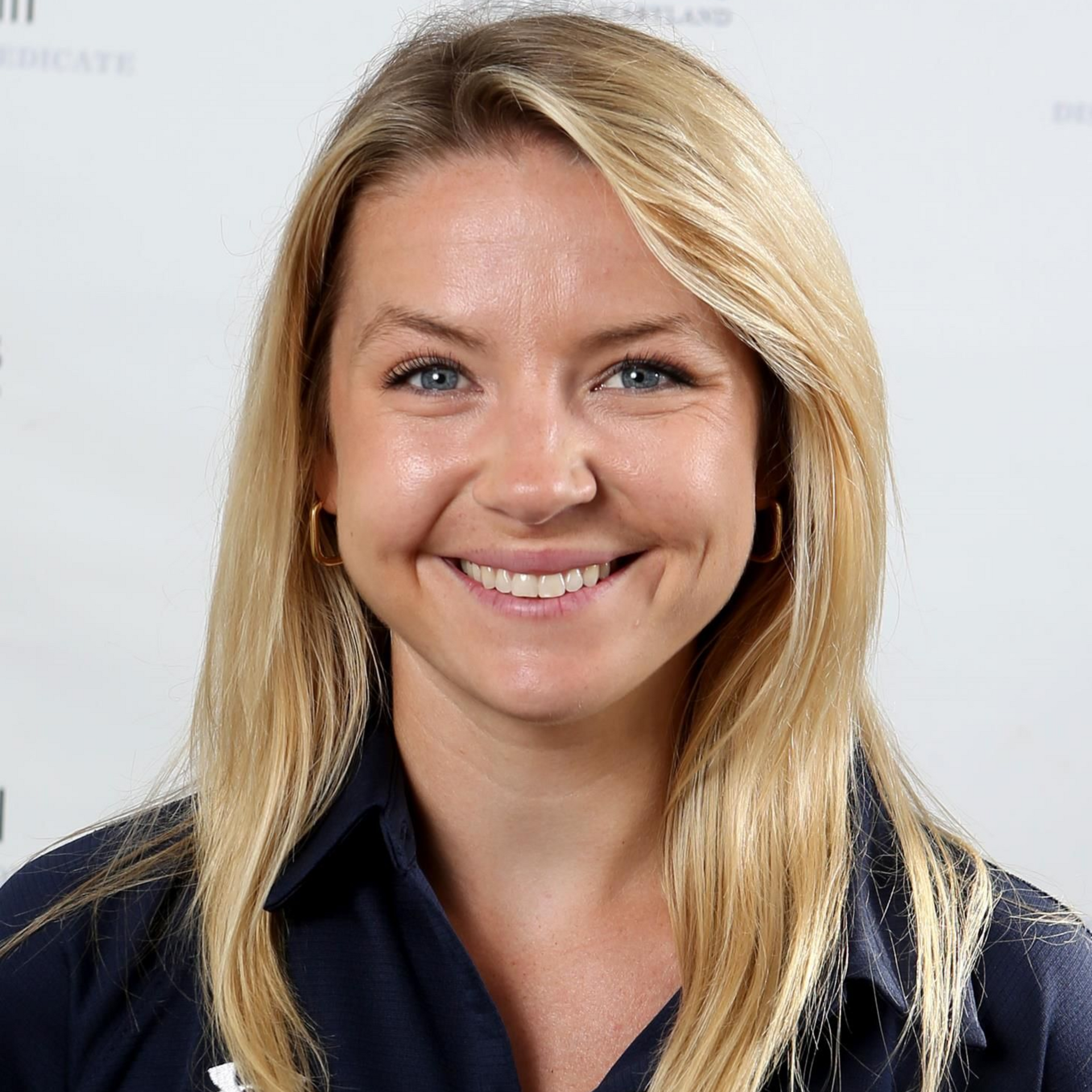 Smiling blonde woman in a navy jacket against a light background