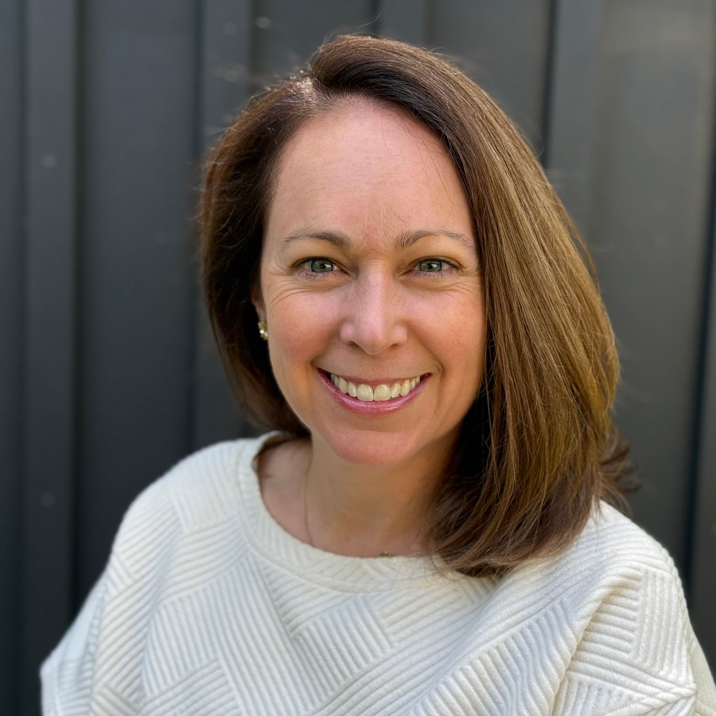 Smiling woman in a white sweater against a dark outdoor backdrop