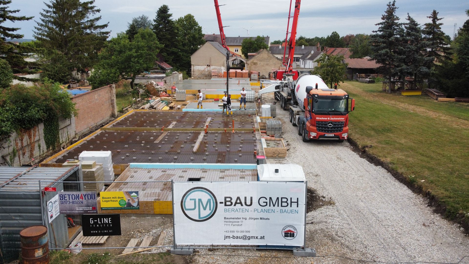 Bauarbeiter mit Schutzhelmen und Westen begutachten an einem Tisch Baupläne.