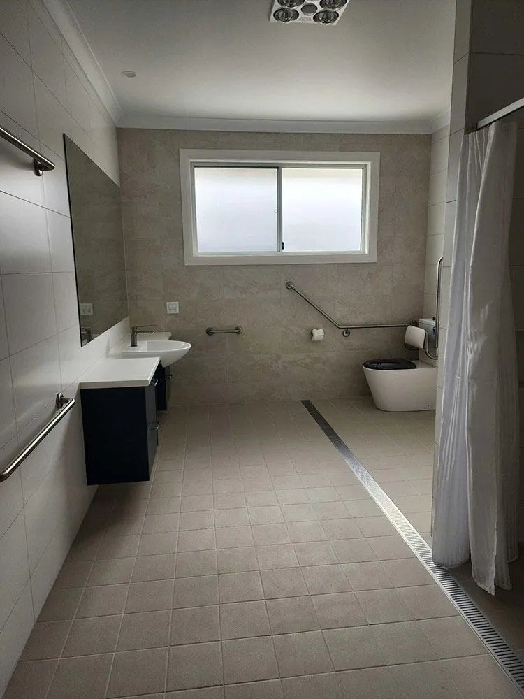 A Bathroom With a Sink , Toilet , Mirror and Shower Curtain — Chandolin Construction in Bathurst, NSW