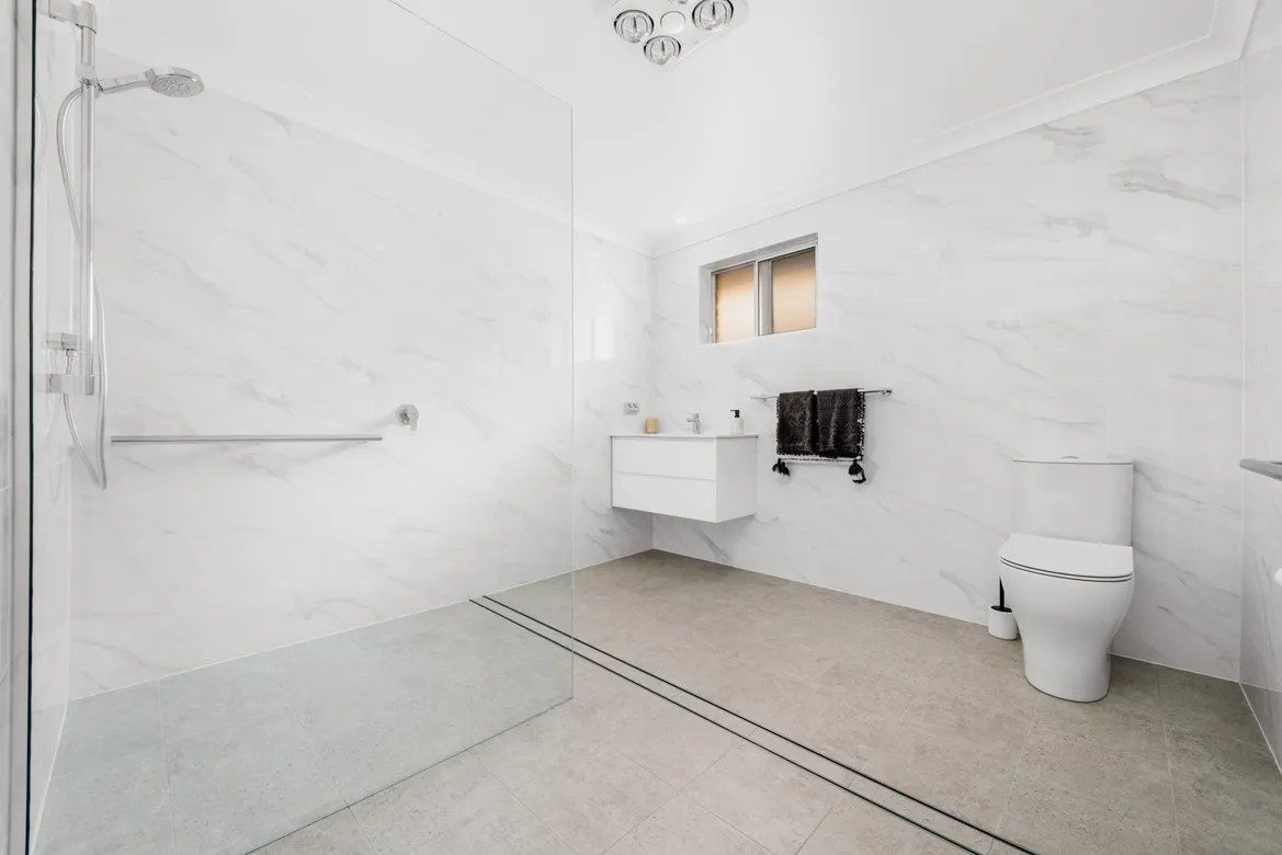 A Bathroom With a Toilet , Sink and Walk in Shower — Chandolin Construction in Bathurst, NSW