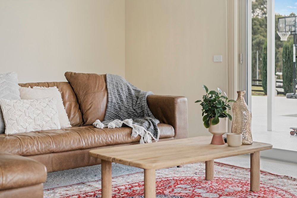 A Living Room With a Leather Sofa and Wooden Table — Chandolin Construction in Bathurst, NSW