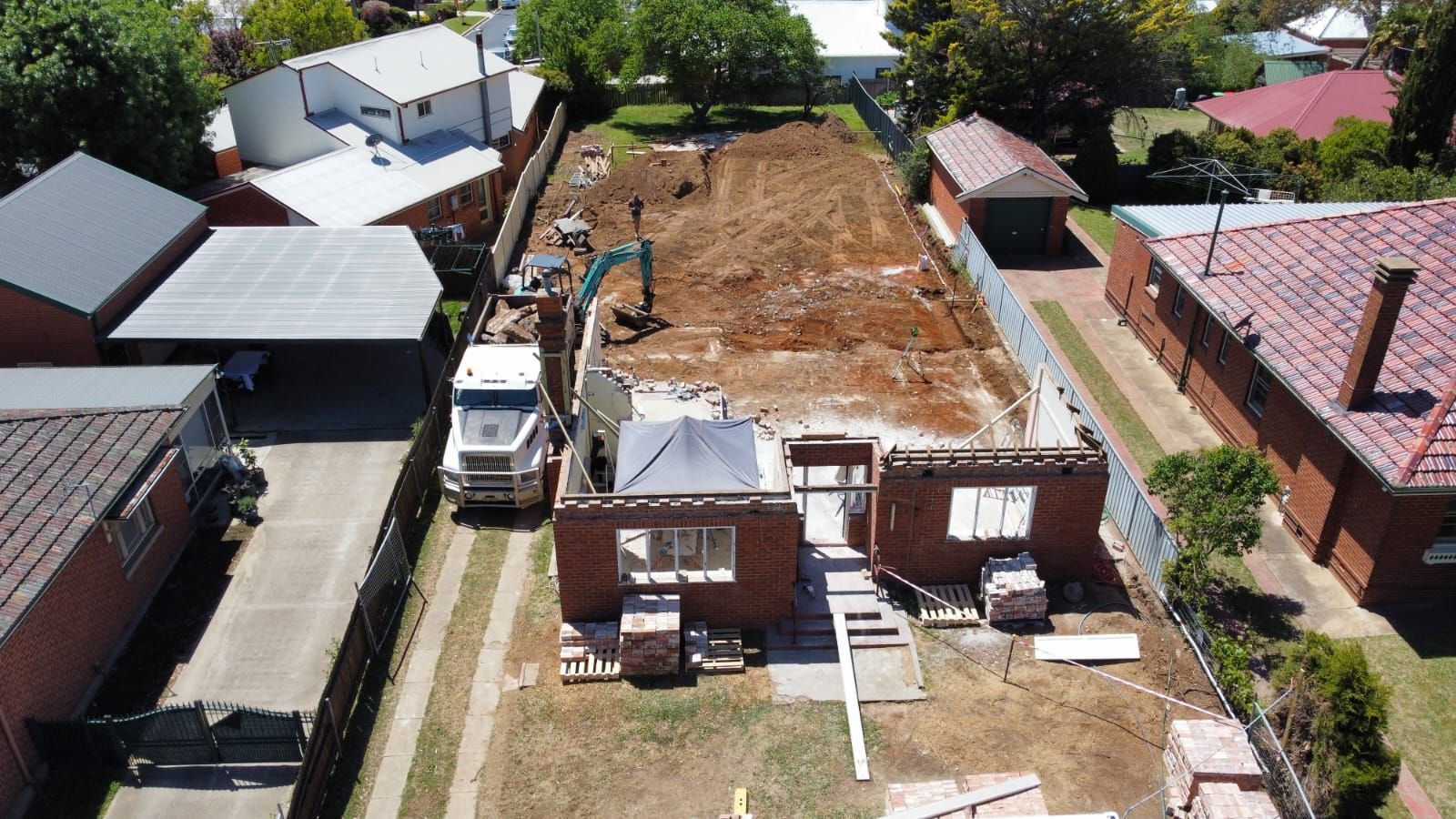 Two Men Wearing Hard Hats and Masks Are Standing Next to Each Other in Front of a Garage — Chandolin Construction in Bathurst, NSW