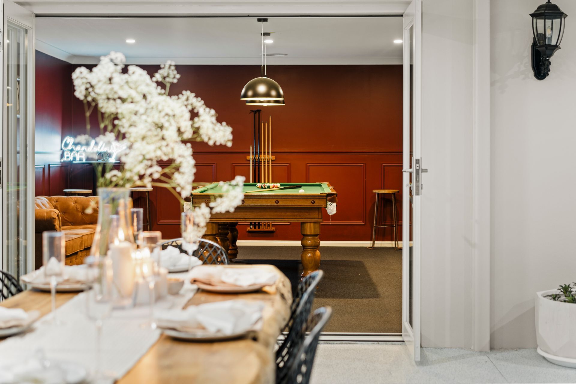 A Dining Table Overlooking a Game Room with A Pool Table and Red Walls — Chandolin Construction in Bathurst, NSW
