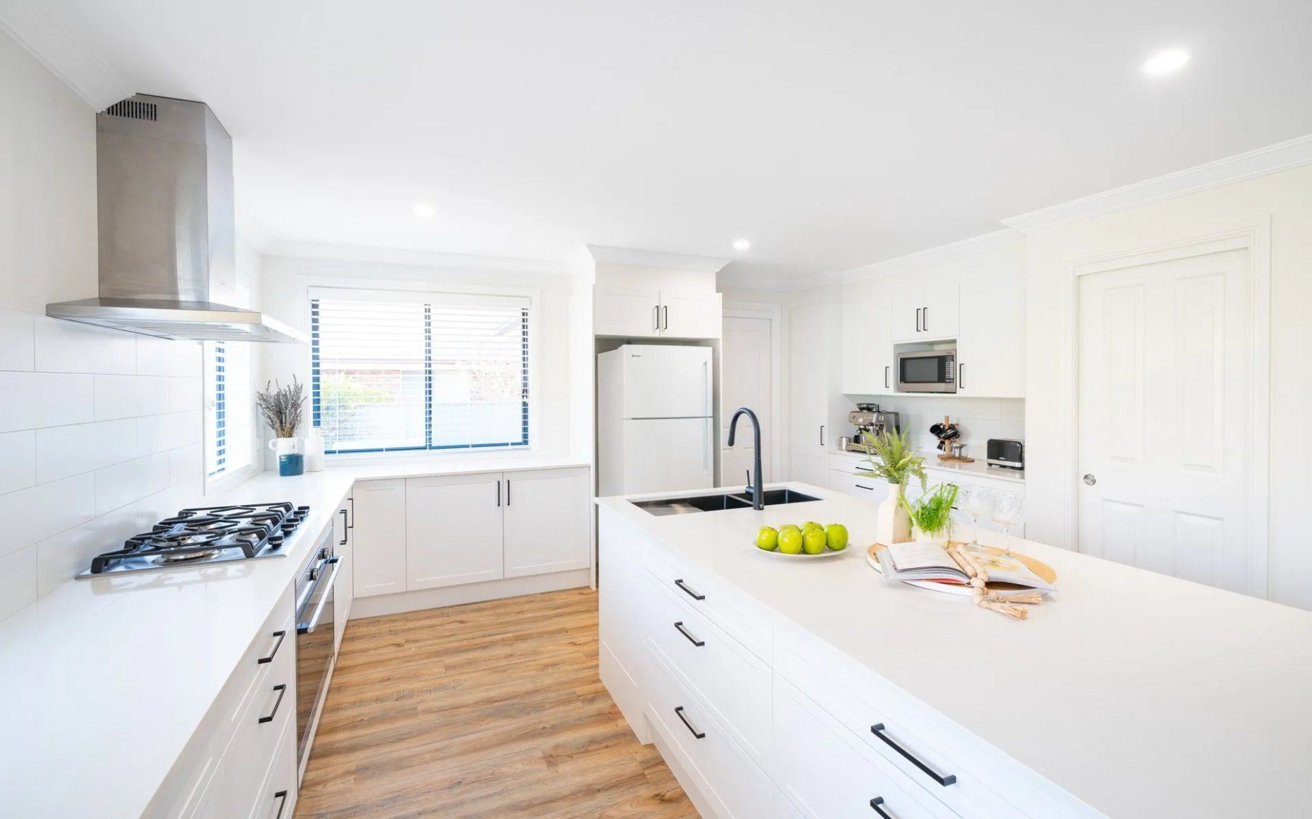 A Kitchen With White Cabinets , Stainless Steel Appliances , and a Large Island — Chandolin Construction in Bathurst, NSW