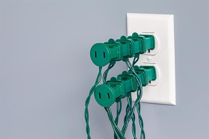 A bunch of green plugs are plugged into a wall outlet