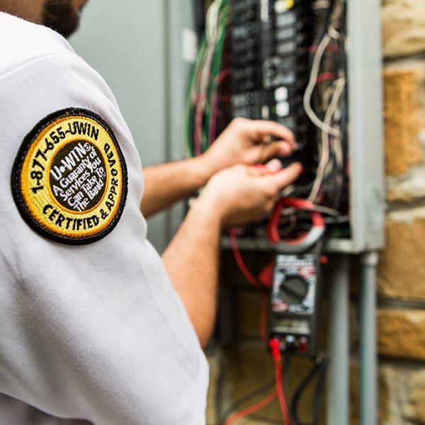 Man in Mister Sparky shirt inspects electrical panel