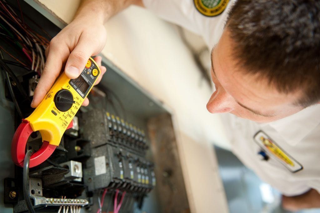 A man is using a clamp meter to test an electrical box.