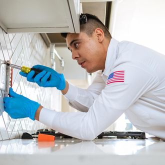 a man in a white shirt with an american flag on his sleeve is working on a electrical outlet